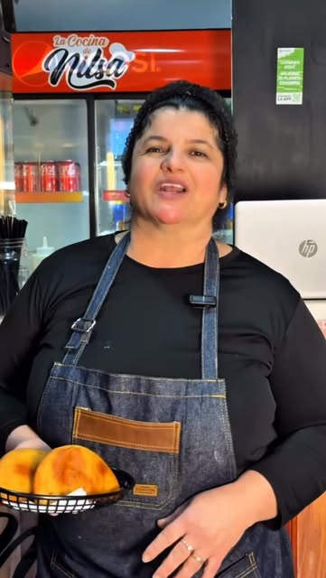 Nilsa en su local, con una canasta de empanadas